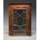 A George III mahogany and inlaid corner cupboard, with moulded cornice above astragal glazed door