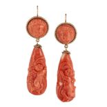 A pair of late 19th century coral earrings, each tapered drop carved with a putto, the circular tops