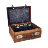 A leather travelling vanity case, fitted with hammered white metal mounted glass vanity jars (
