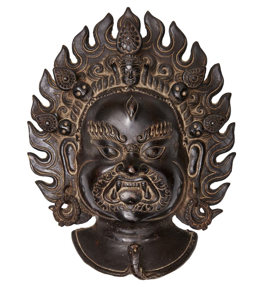 A Tibetan bronze plaque of Mahakala, 19th century, cast with flame halo, loose earrings, and serpent