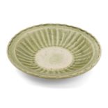 A Vietnamese stoneware green-glazed dish, 14th century, with pinched petal design to the interior