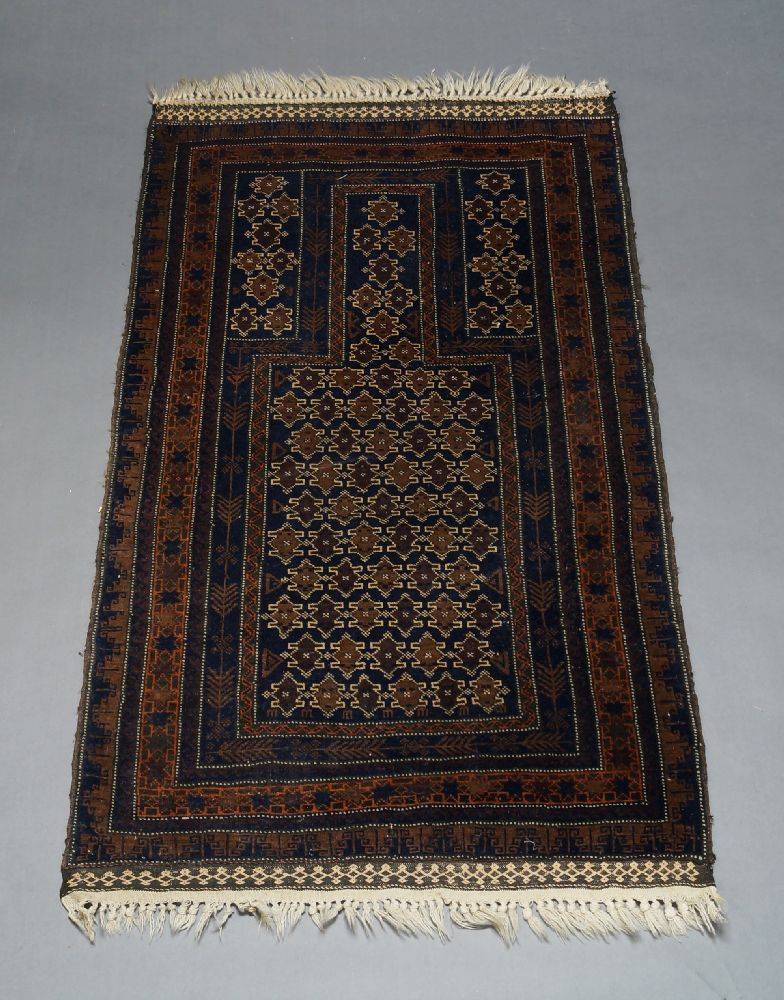 A Belouch prayer rug, the charcoal ground mihrab, with repeat design, set within multiple borders,