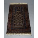 A Belouch prayer rug, the charcoal ground mihrab, with repeat design, set within multiple borders,