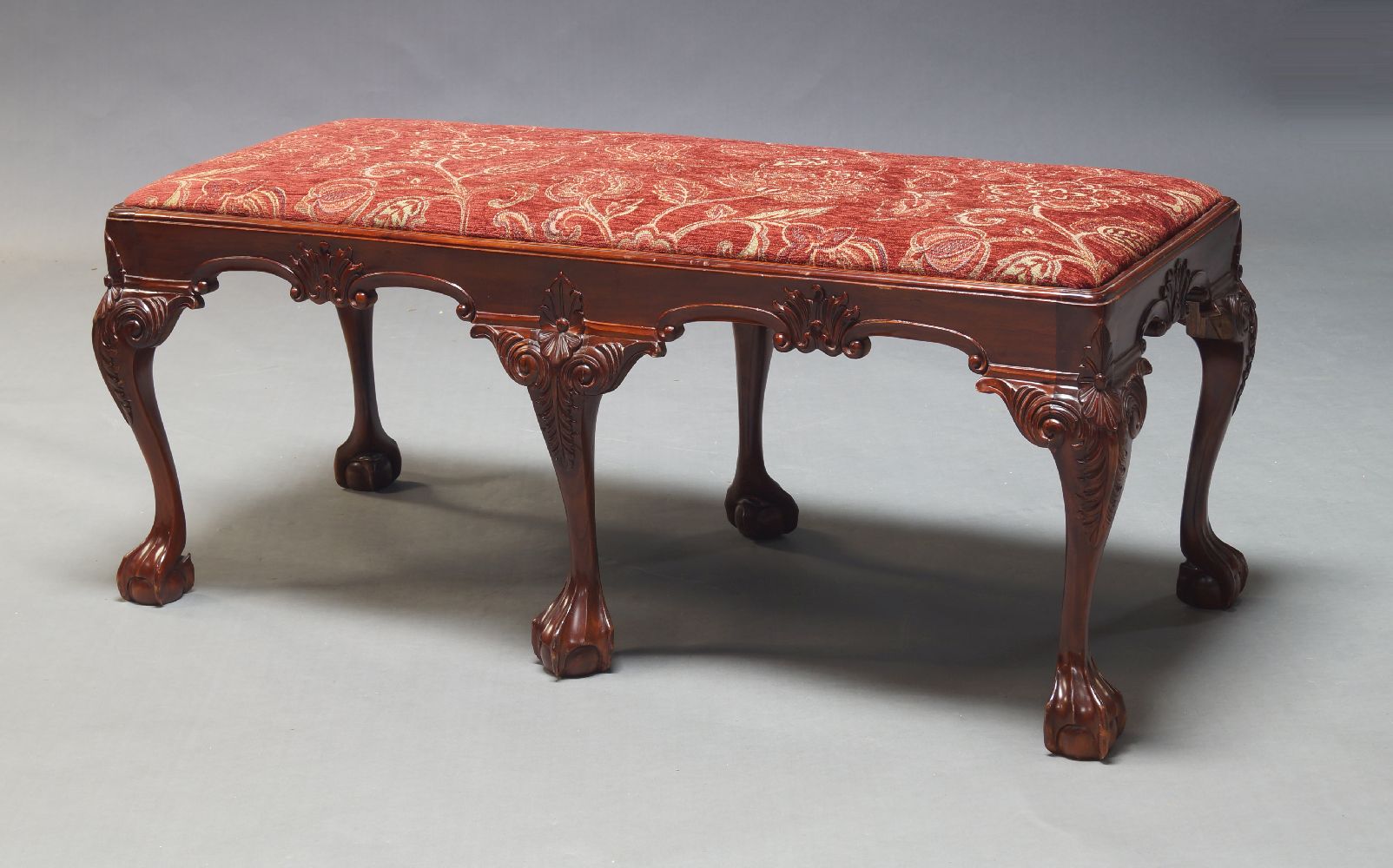 A George II style mahogany window seat, late 20th Century, the burgundy floral upholstered seat on