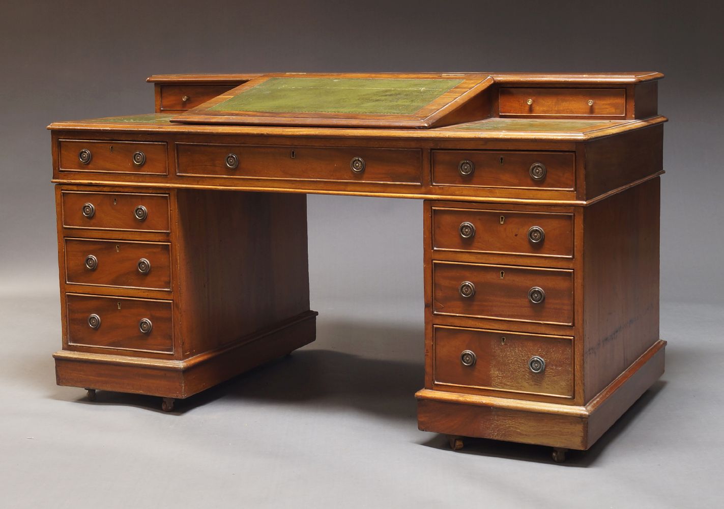 An Edwardian mahogany pedestal desk, the top inset with green leatherette, having hinged writing