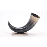 An ornamental ox drinking horn with white metal rim, mounted on a brushed metal base, 25cm high,