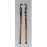 A pair of African painted walking sticks, late 20th Century, carved as a man and woman, each approx.