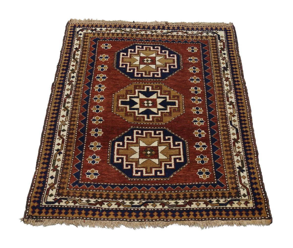 A Shirvan rug, mid to late 20th century, with three star centred octagons in a deep red field