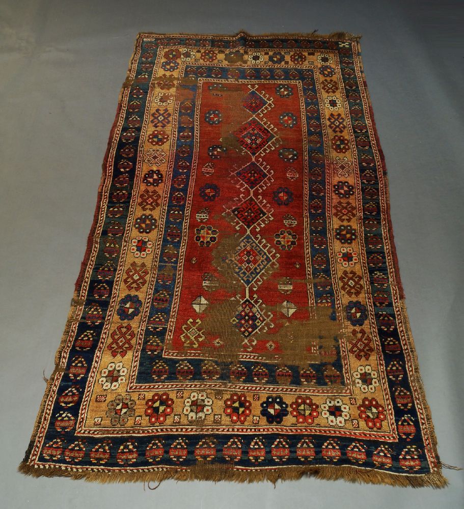 A Kazak rug, early to mid 20th Century, with six hook edged medallions in a red field, 260cm x 128cm