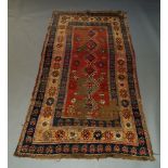 A Kazak rug, early to mid 20th Century, with six hook edged medallions in a red field, 260cm x 128cm