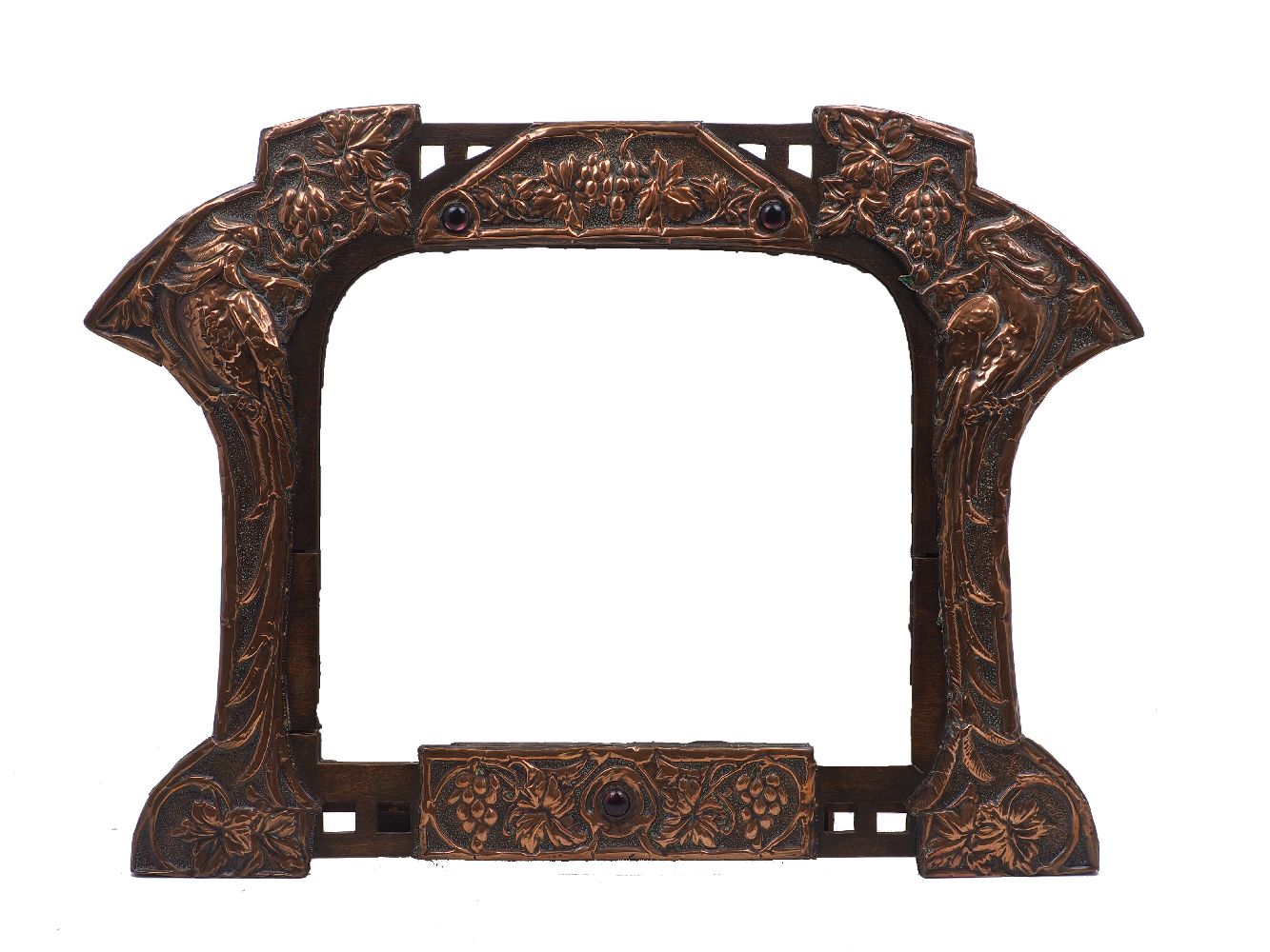 An Arts & Crafts repousse copper on wood mirror, early 20th century, the arched plate flanked by