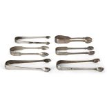 A group of six monogrammed Georgian silver sugar tongs, comprising a pair of George IV tongs,