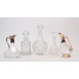 Three clear glass decanters and two ewers, 20th century, the ewers with white metal mounts, 23-
