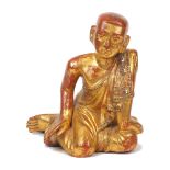 A Thai giltwood Buddha, early 20th century, depicted kneeling, inset with coloured glass, 28cm