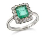 An emerald and diamond cluster ring, the rectangular-cut emerald within a brilliant-cut diamond