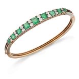 A late 19th century emerald and diamond bangle, of hinged half-hoop design, composed of a line of