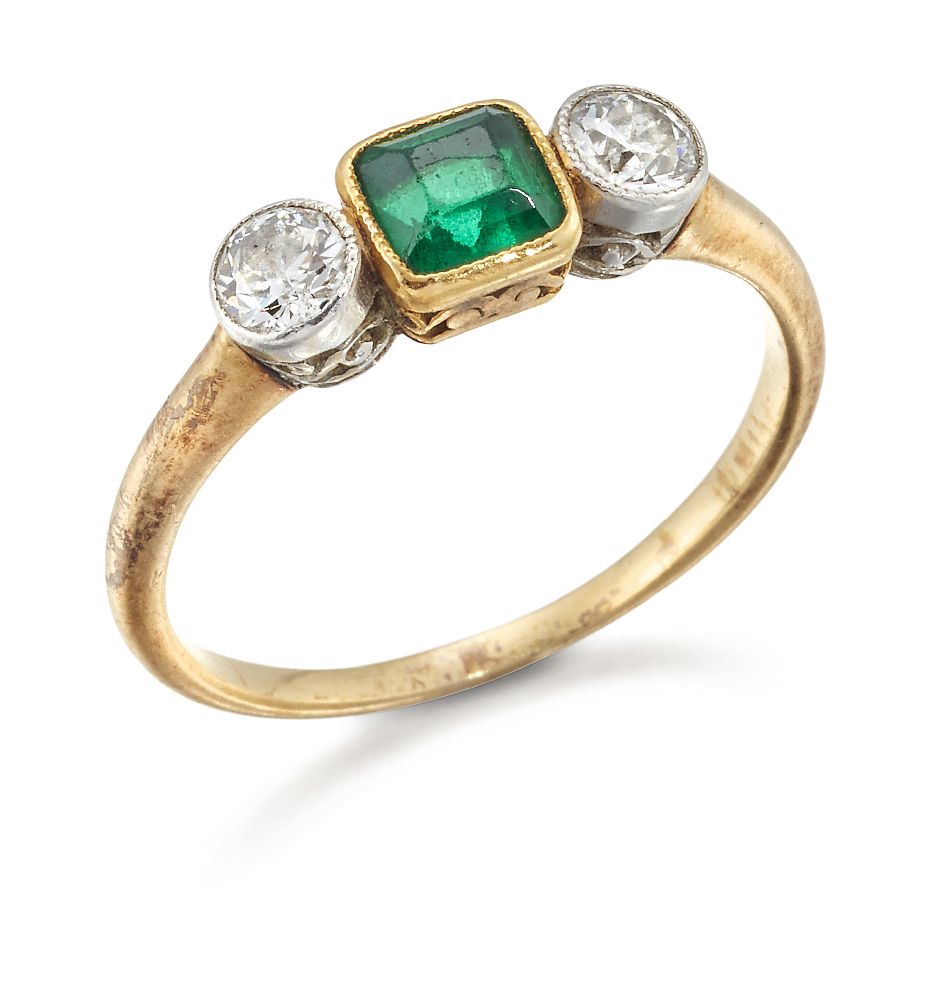 An early 20th century emerald and diamond three stone ring, the central cut-cornered square