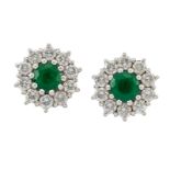 A pair of emerald and diamond circular cluster earstuds, the circular emeralds within brilliant-