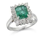 An emerald and diamond cluster ring, the rectangular claw-set rectangular-cut emerald with