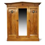 An Arts and Crafts oak triple wardrobe manufactured by Lebus, Louis & Harris, c.1905, The arched