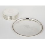 A set of twelve silver plated place mats, of circular form, with ringed decoration and felt