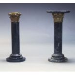 A pair of black and white variegated marble columns, 20th Century, with shaped top (one lacking top)