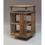 An Edwardian oak revolving bookcase, of square form, with upper section raised on three columns (one