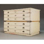 A white painted plan chest, early 20th century, in two sections, with six drawers having shell cup