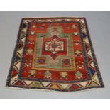 A Kazak rug with central medallion with mirror panel, with green and ivory colours on red ground,