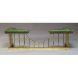 An Arts and Crafts style brass and green leather upholstered club fender, 20th Century, with tubular