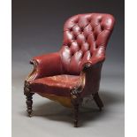 A Victorian button back armchair, upholstered in burgundy leather, with carved scrolling arms, on