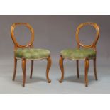 A pair of mid Victorian walnut balloon back dining chairs, with carved crest rails, overstuffed