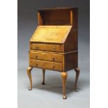 A figured walnut bureau de dame, early 20th Century, the top with open shelf above fall enclosing