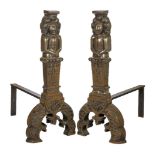 A pair of large cast iron fire dogs, 17th century style, the uprights each cast with a figural