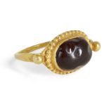 A garnet set gold ring, the oval garnet in a gold setting with bead decoration and two large balls