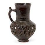 An aubergine-glazed openwork jug, Iran or Central Asia, 13th century, with short spreading foot,