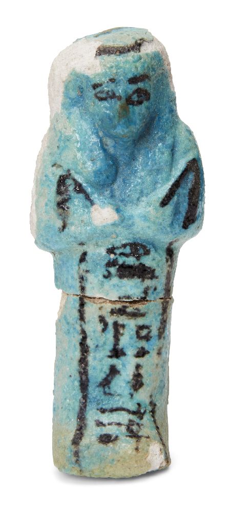 An Egyptian turquoise glazed composition shabti with black glazed details, holding two hoes, with