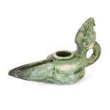 A green glazed pottery lamp, possibly Spain, 10th century, of rounded form with a long spout and