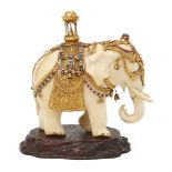 A gem-set, gilt-silver mounted ivory elephant, Ceylon (Sri Lanka), circa 1910, on an oval wood base,