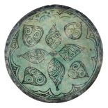 A large Kubachi ware turquoise and black glazed pottery dish, Iran, 17th century or earlier, on a