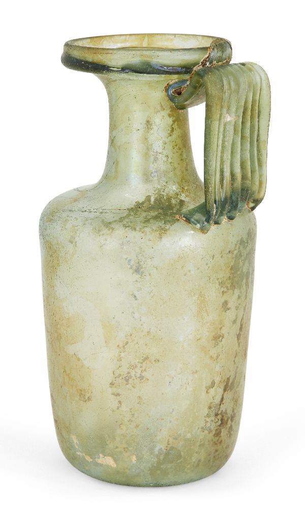 A Roman green glass flask, 1st-3rd century AD, on an indented base, rounded sides and ribbed handle,