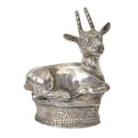 A hollow silver finial in the form of a recumbent mountain goat with curved horns and naturalistic