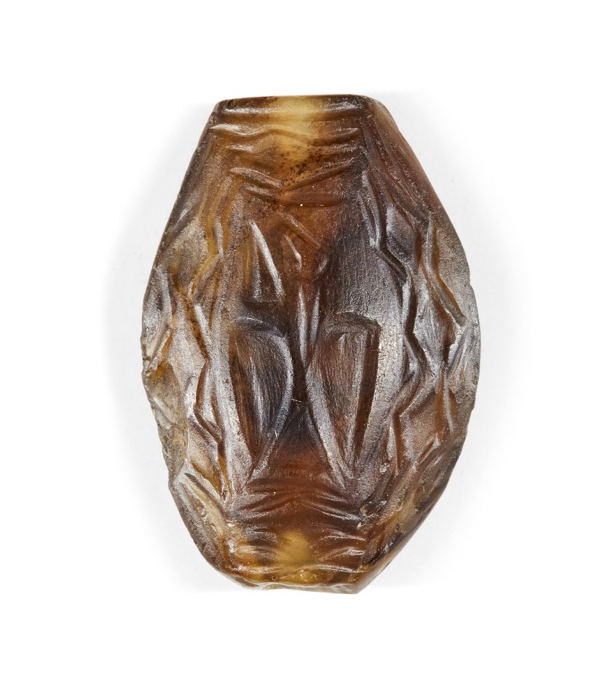 A Western Asiatic banded agate bead, circa 2nd millenium B.C., of elliptical form, carved to one