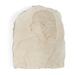 An Egyptian style limestone relief fragment with the profile bust of a male with well delineated