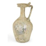 A Roman clear glass ewer, circa 1st-2nd century AD., the base with indented foot, globular ribbed