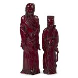 A pair of Chinese cherry amber figures, early 20th century, carved as two standing deities, 21 and