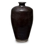 A Chinese pottery black-glazed vase, Ming dynasty, the lustrous black glaze covering the ribbed body