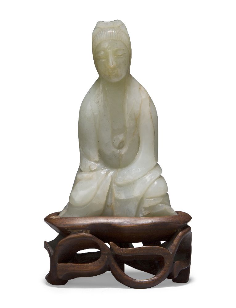 A Chinese pale green jade ‘Guanyin’ carving, 19th century, carved seated with her long robes wrapped