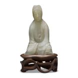 A Chinese pale green jade ‘Guanyin’ carving, 19th century, carved seated with her long robes wrapped