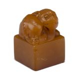 A Chinese hardstone square seal, early 20th century, the amber coloured stone carved with a